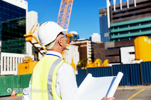 建筑工地的工程師建設者工程師建筑工人施工場景穿著帶藍圖的安全背心